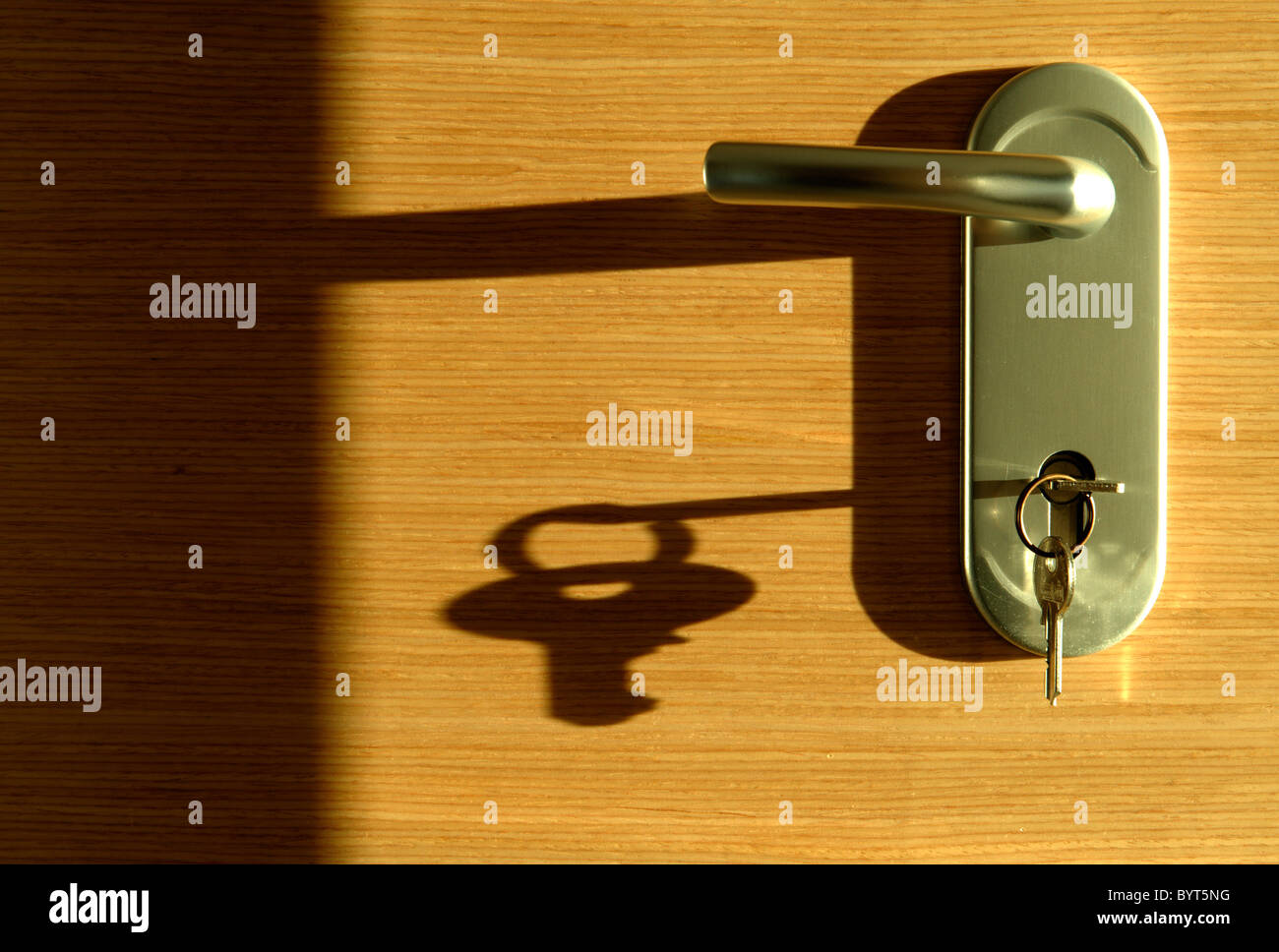 Schlüssel im Türschloss wirft einen langen Schatten Stockfoto