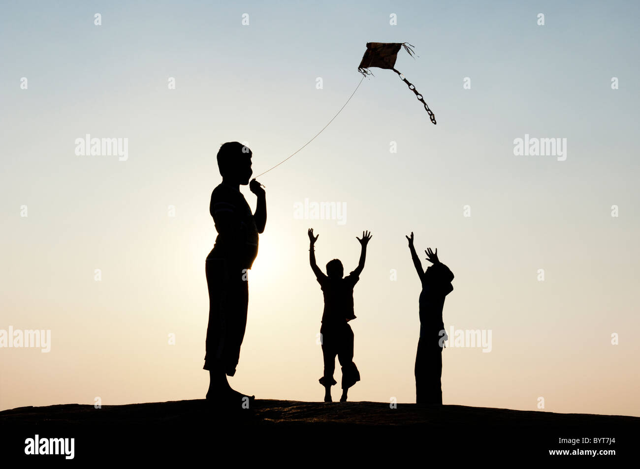 Indischen Jungen Spaß ein handgeschöpftes Papier Drachen in der indischen Landschaft. Silhouette Stockfoto