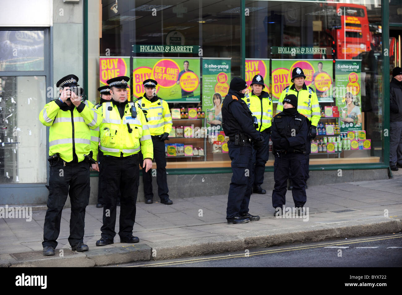 Sussex Polizisten fotografieren und beobachten eine kleine Gruppe von Demonstranten während einer Demonstration von UK Uncut auf Stiefel in Brighton Stockfoto