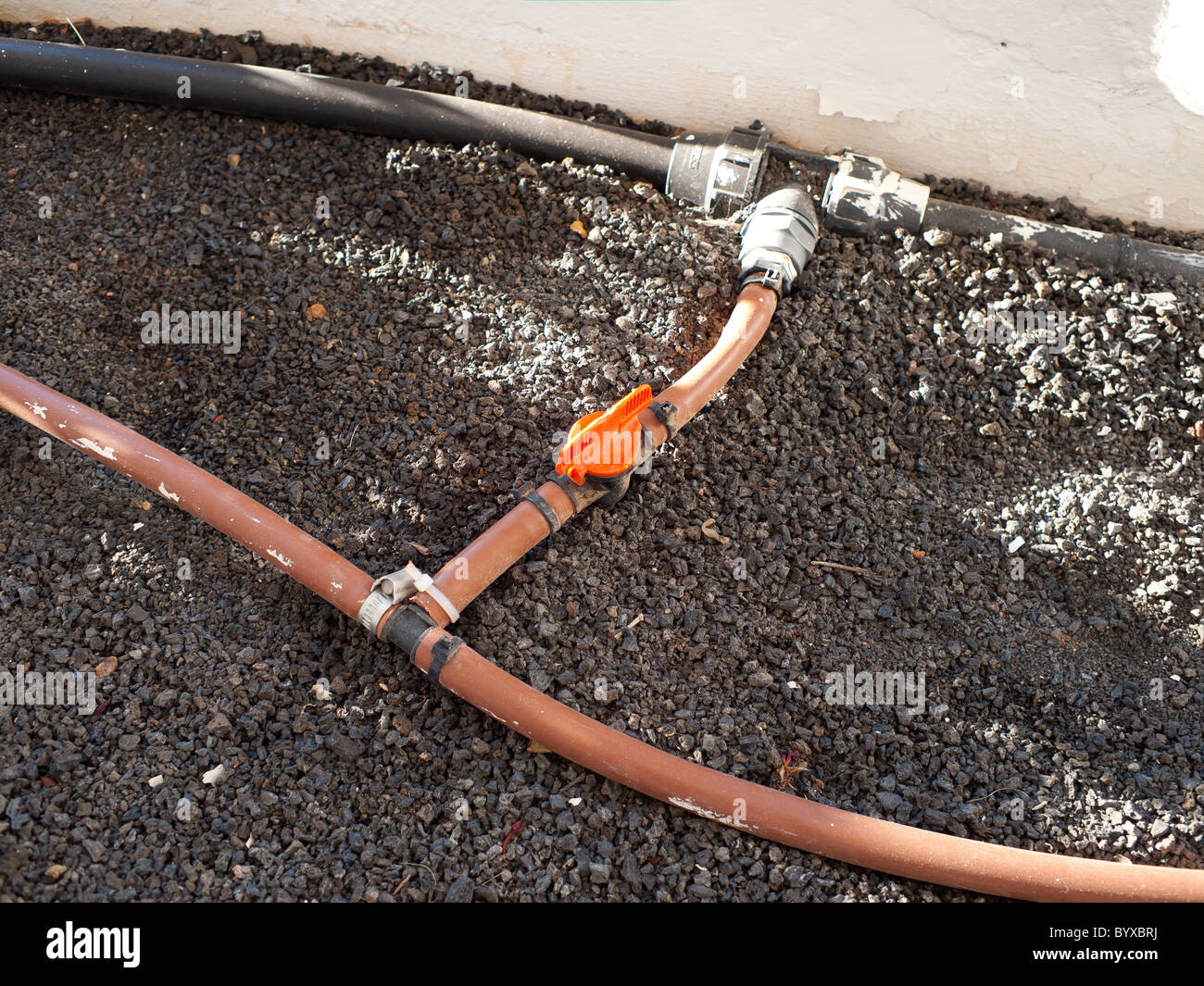 Kunststoffrohr-Arbeit für eine permanente Bewässerungs-System für ein Blumenbeet auf dem Hotelbalkon Stockfoto