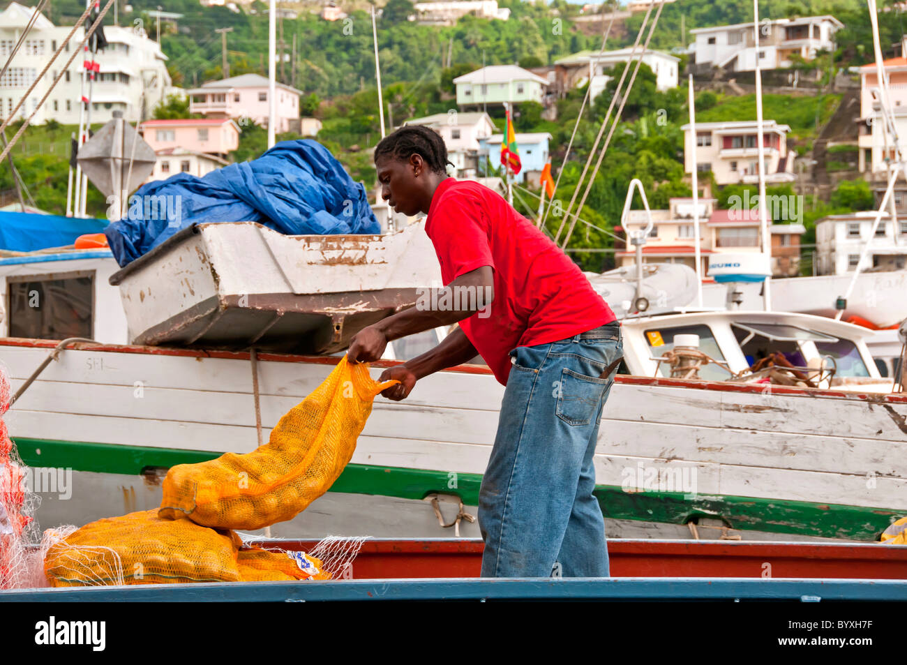 Grenada St Georges Carenage Harbour dock Arbeiter im roten Hemd laden Produkte auf kommerzielle Schiff Stockfoto