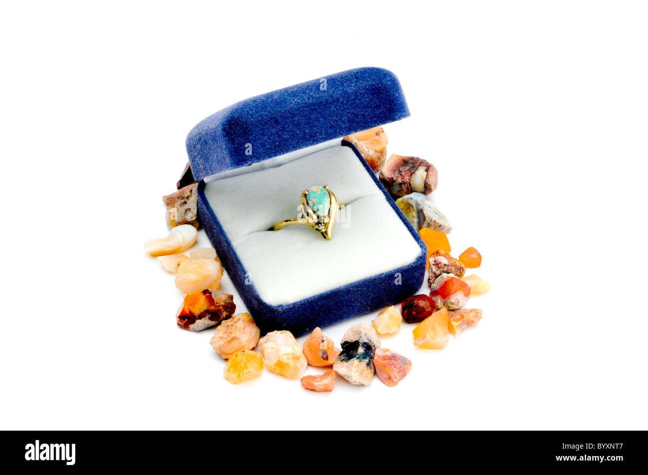 Opal und Gold Ring im blauen Kasten auf weiss umgeben von rohe Edelsteine Stockfoto