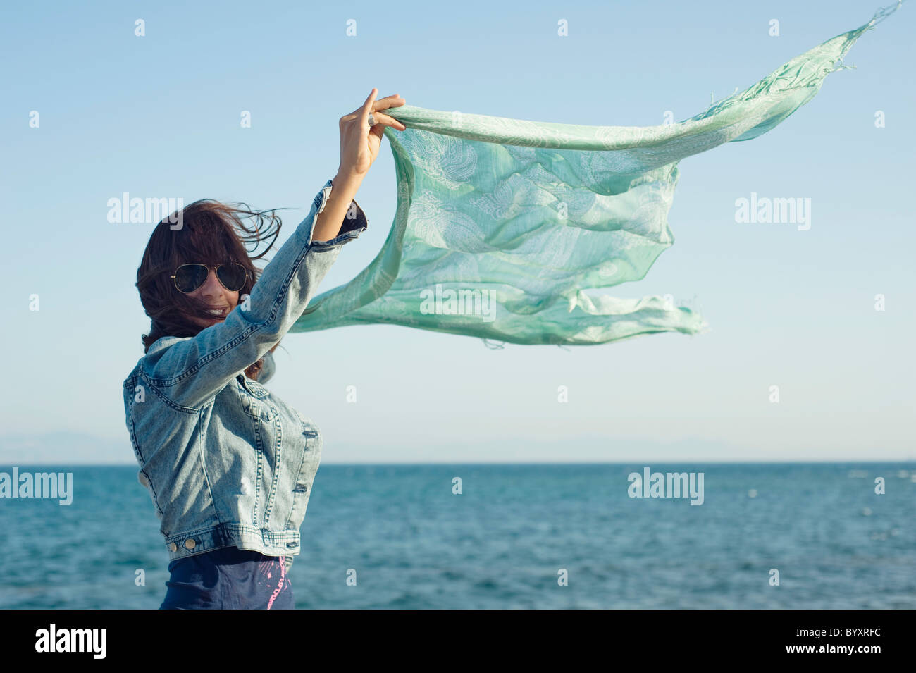eine Frau hält einen Schal draußen im Wind am Meer am Parque natural del Estrecho; Tarifa, Cádiz, Andalusien, Spanien Stockfoto