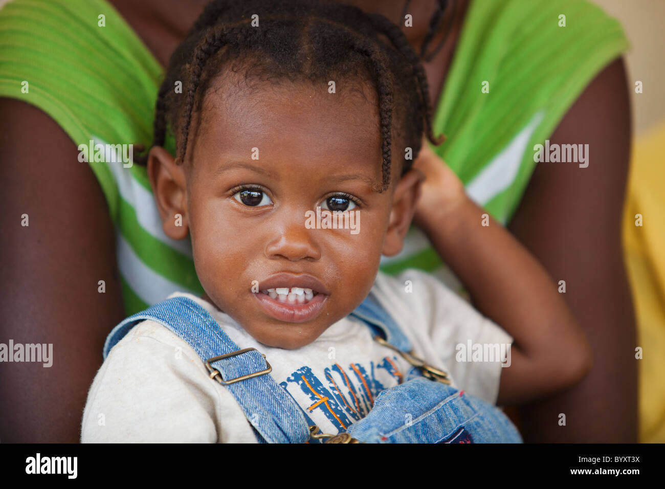 ein junges Mädchen in einem Erwachsenen Armen gehalten; Grand Saline, haiti Stockfoto