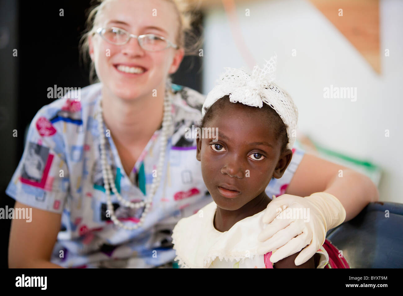 eine Krankenschwester sitzt mit einem Mädchen in einer Klinik; Grand Saline, haiti Stockfoto