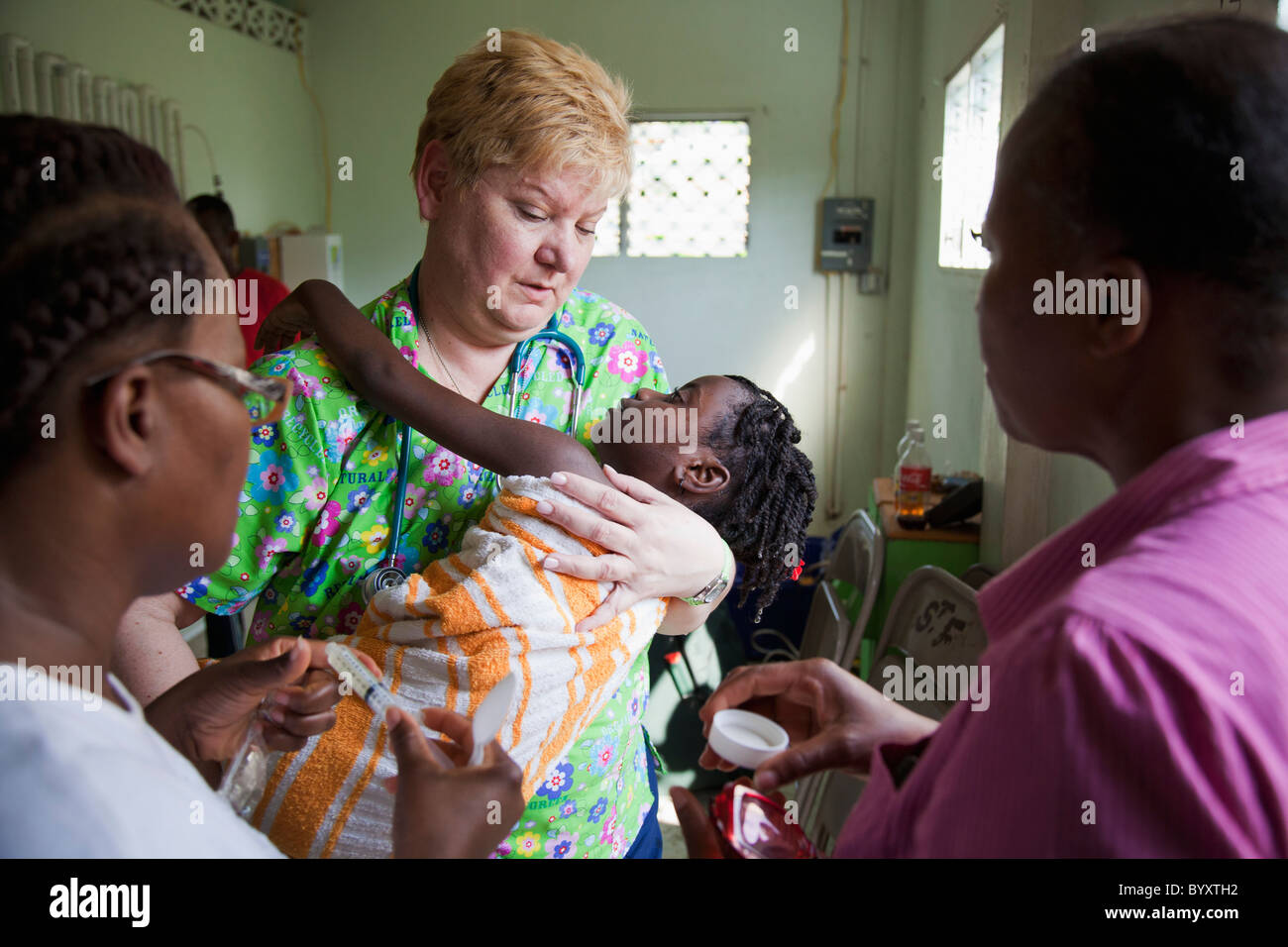 eine freiwillige Krankenschwester kümmert sich um ein Kind, das von Anfällen leidet; Grand Saline, haiti Stockfoto