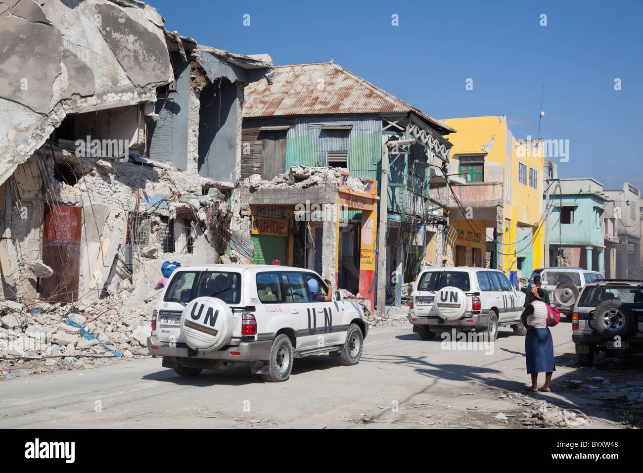 Ruinen von Gebäuden mit UN-Fahrzeugen, die durch eine Straße in der Innenstadt zu reisen; Port-au-Prince, haiti Stockfoto