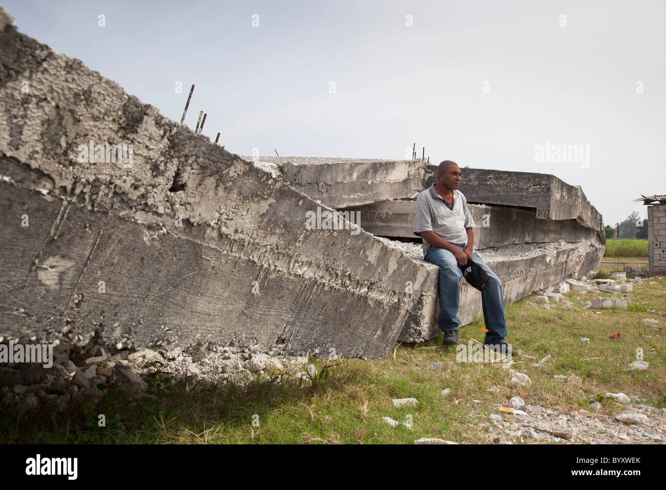 ein Mann sitzt auf dem Beton eine drei-geschossiges Gebäude, die bei dem Erdbeben; zusammengebrochen Port-au-Prince, haiti Stockfoto