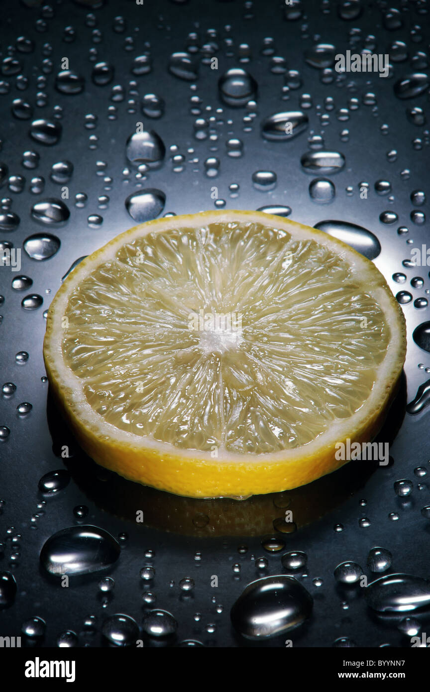 Zitronenscheibe, Wassertropfen, dramatische Beleuchtung, vertikal Stockfoto