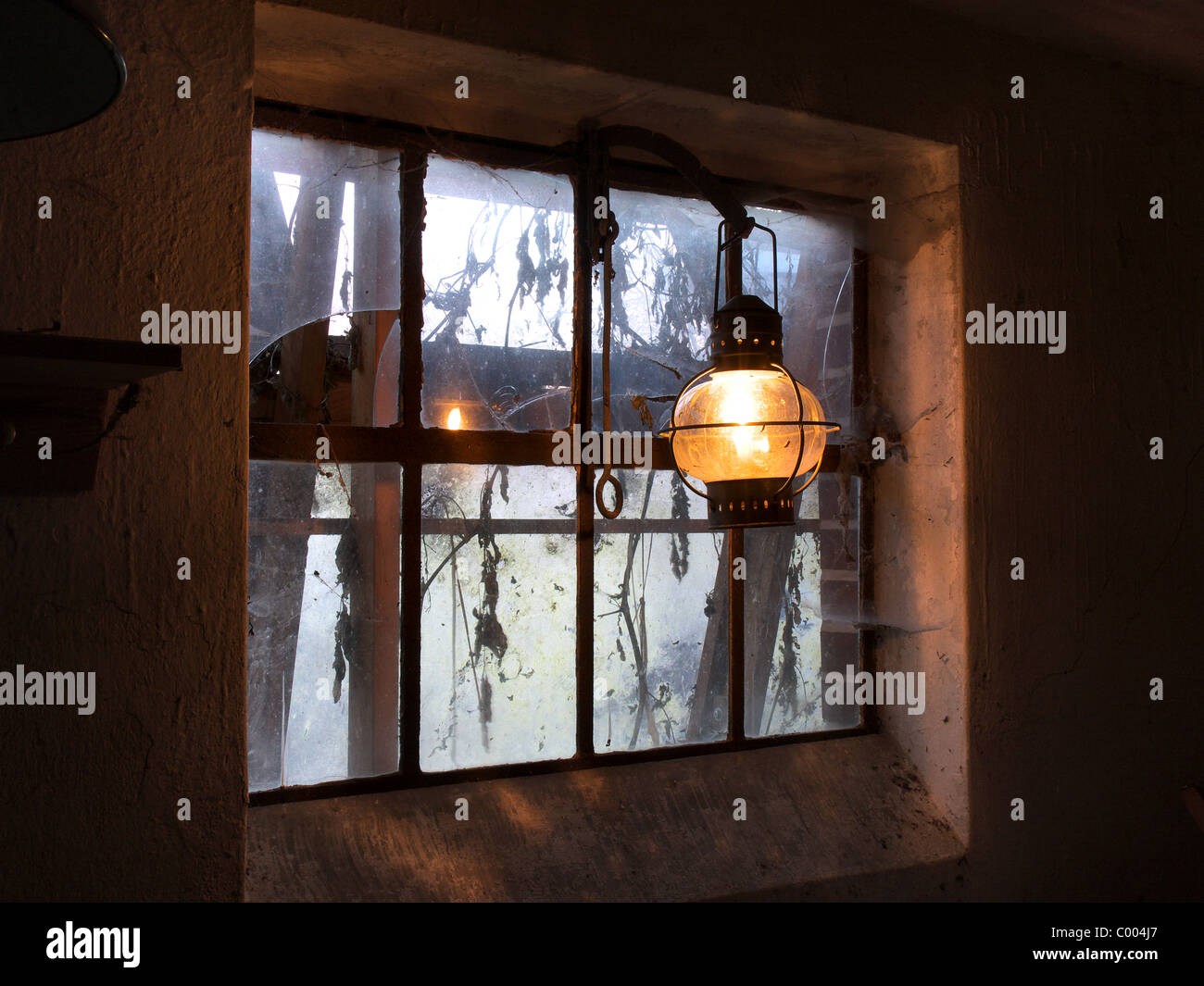 Alte Laterne in einem gebrochenen Schweinestall-Fenster. Stockfoto