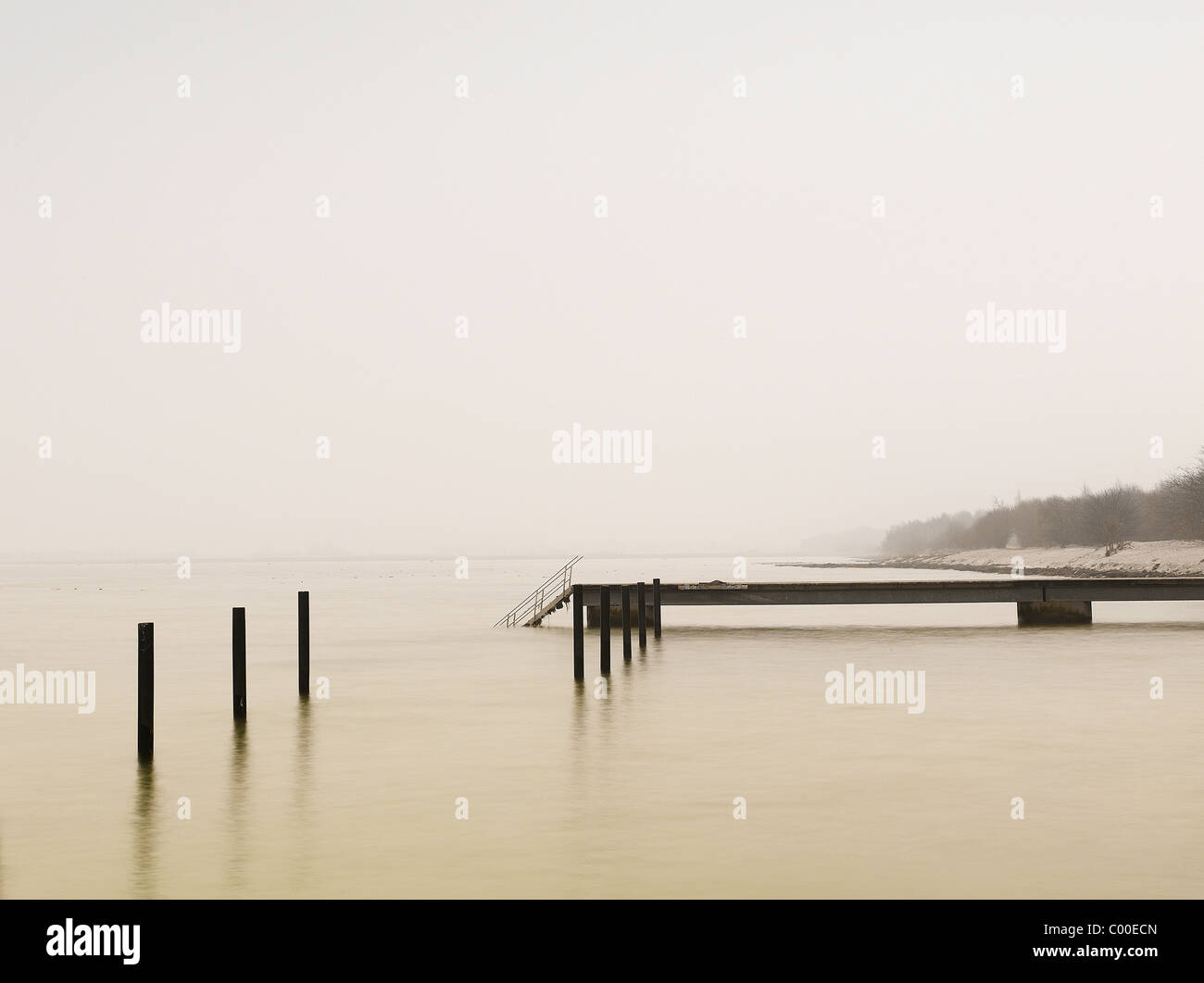 Pier am nebligen See im Morgengrauen Stockfoto