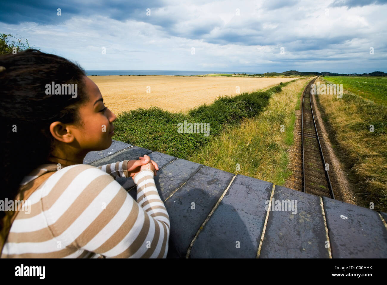 Junge Frau auf der Brücke mit Blick auf Bahngleise Stockfoto