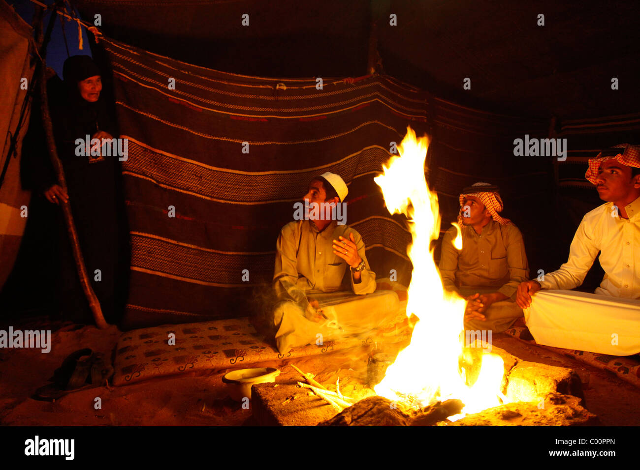 Beduinen sitzen um das Feuer in ihr Lager, Wadi Rum, Jordanien. Stockfoto