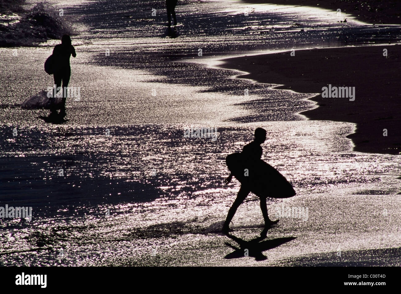 Silhouetten von Surfer am Strand Stockfoto