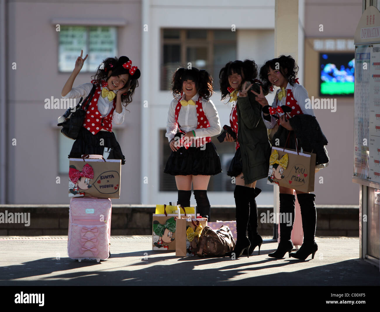 Japanische Mädchen Minnie Maus Kostüme tragen geben Peace-Zeichen, Kamera, Bahnhof Beppu, Kyushu, Japan. Stockfoto