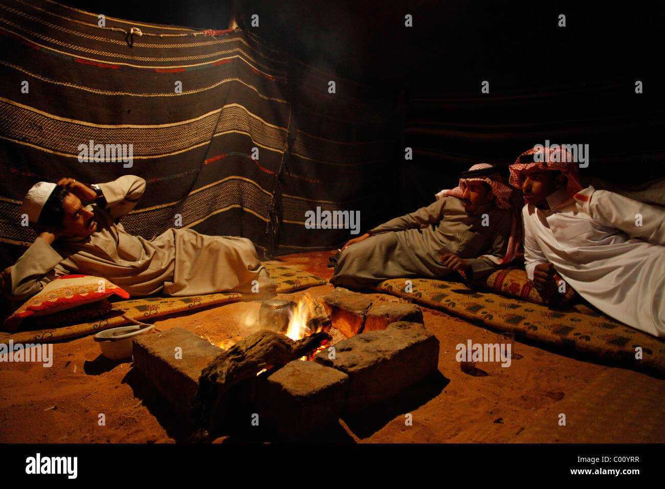 Beduinen sitzen um das Feuer in ihr Lager, Wadi Rum, Jordanien. Stockfoto