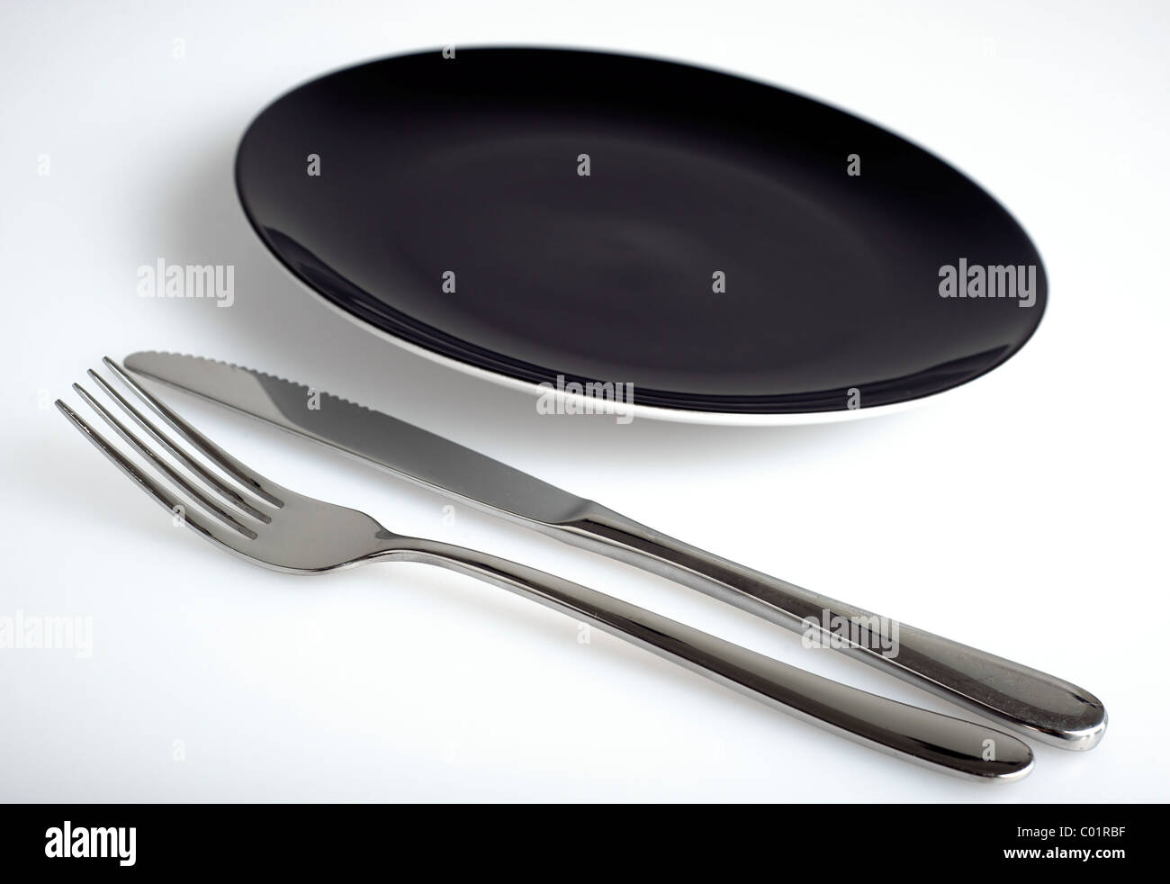 Leeren schwarzen Teller mit Messer und Gabel Stockfoto