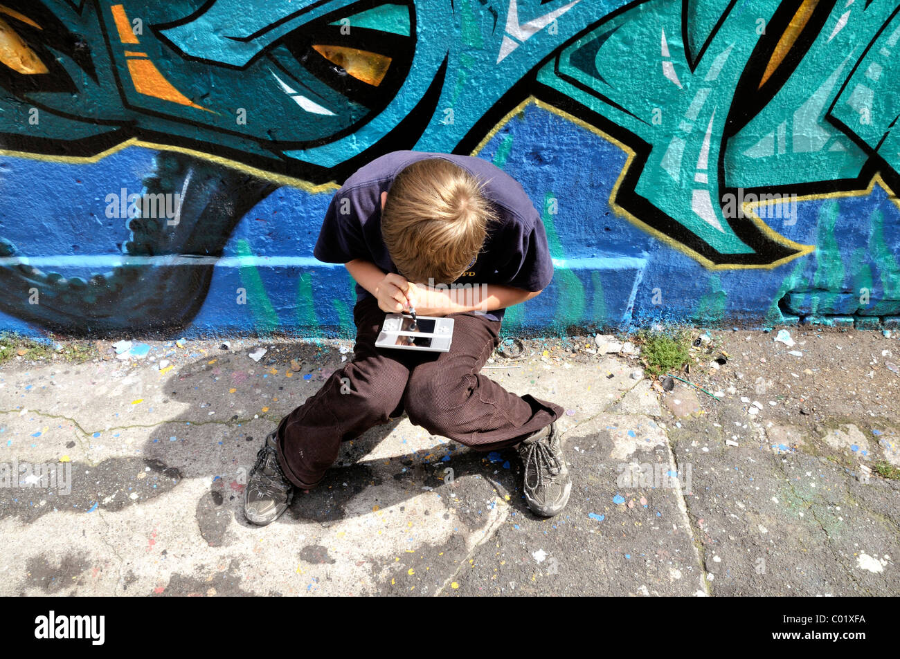 Ten-Year-Old Boy spielt mit seinem Nintendo vor einer Graffiti-Wand,  Deutschland, Europa Stockfotografie - Alamy