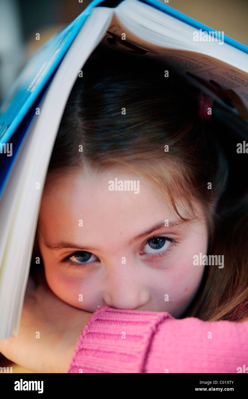 Kind mit einem Buch auf dem Kopf wollen nicht lesen Stockfoto