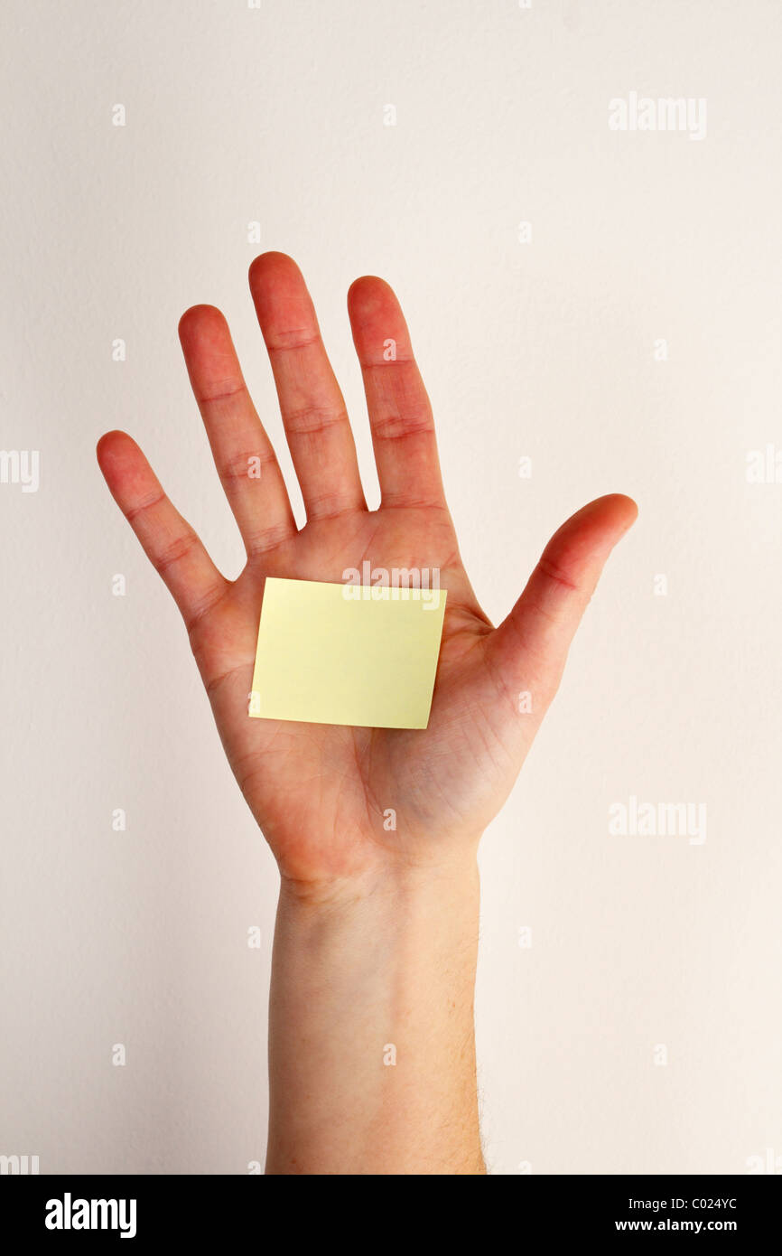 die Hand einer Frau mit einem leeren gelben Zettel geklebt auf die Handfläche und aus weißem Hintergrund Stockfoto