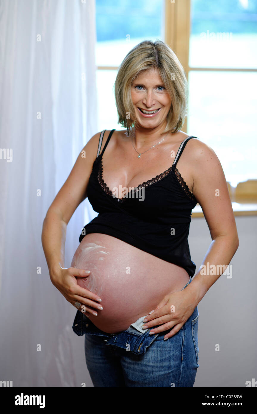 Schwangere Frau auf den Bauch eincremen Stockfotografie - Alamy