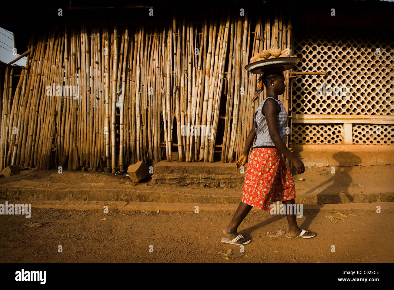 Eine Mädchen trägt Kokosnüsse geht auf eine Straße in Makeni, Sierra Leone auf Mittwoch, 25. Februar 2009. Stockfoto