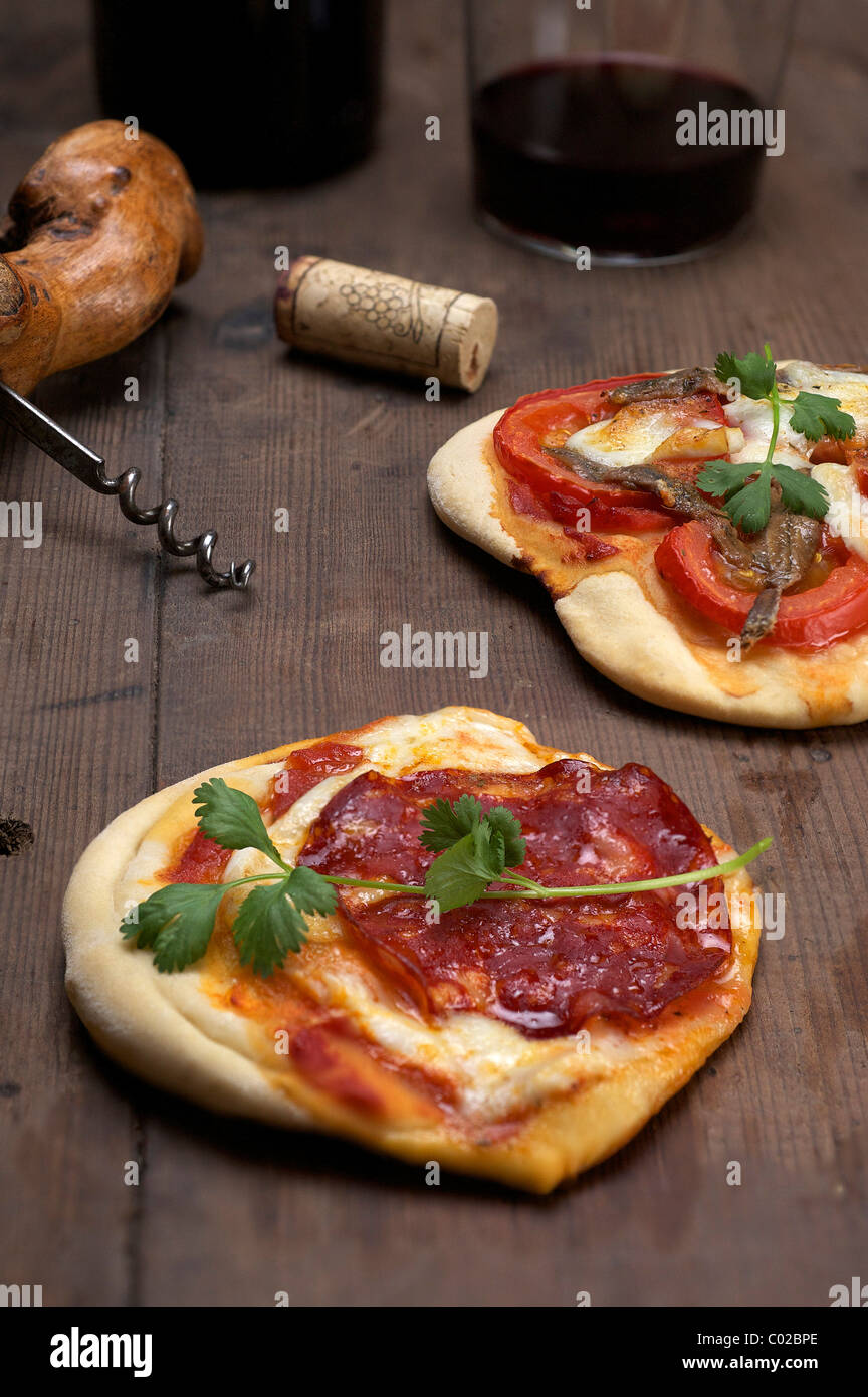 Pizzette, kleine Pizzen mit Büffel-Mozzarella, Chorizo und Koriander, vorne, und Tomaten und Anchovis, hinten Stockfoto
