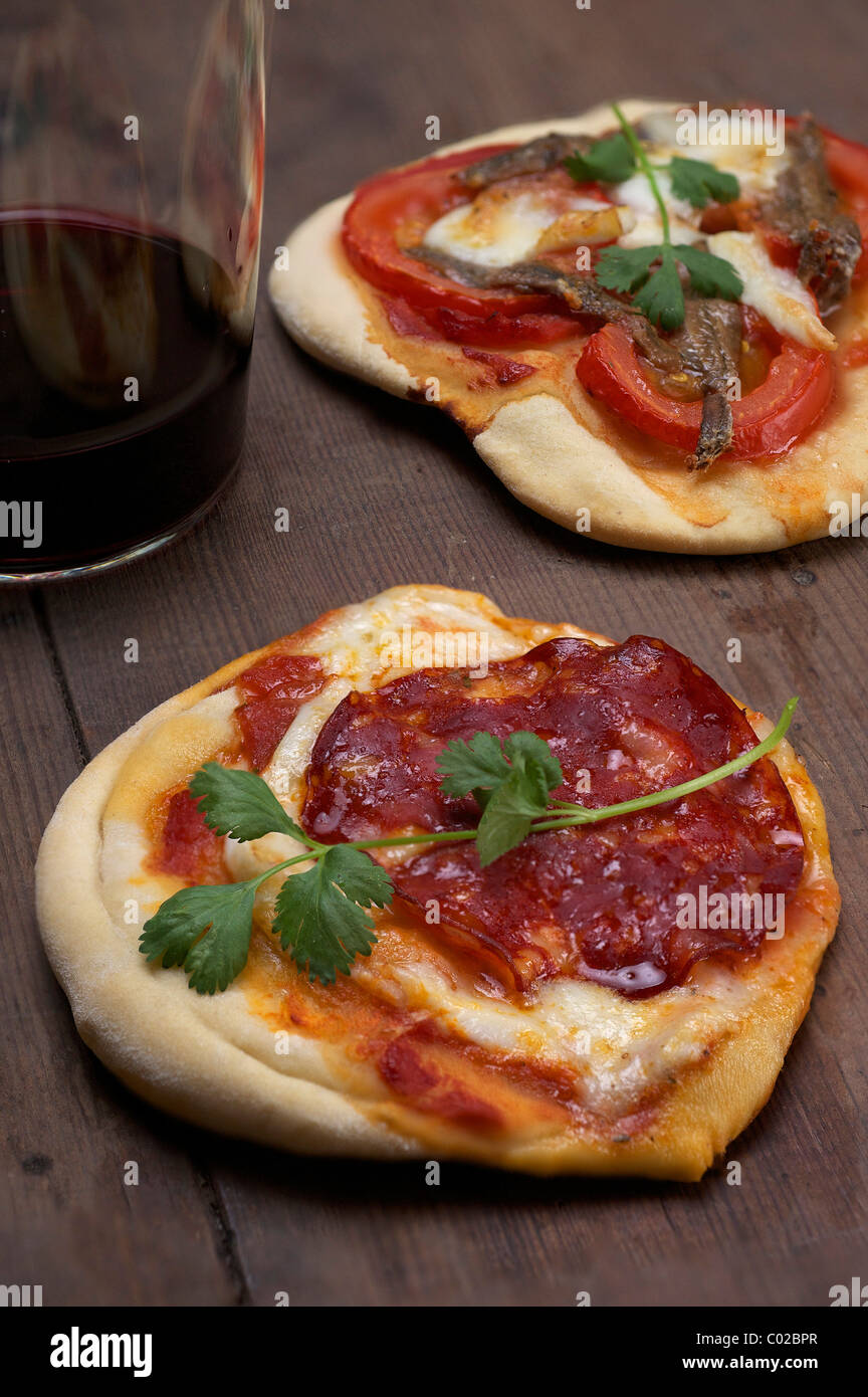 Pizzette, kleine Pizzen mit Büffel-Mozzarella, Chorizo und Koriander, vorne, und Tomaten und Anchovis, hinten Stockfoto
