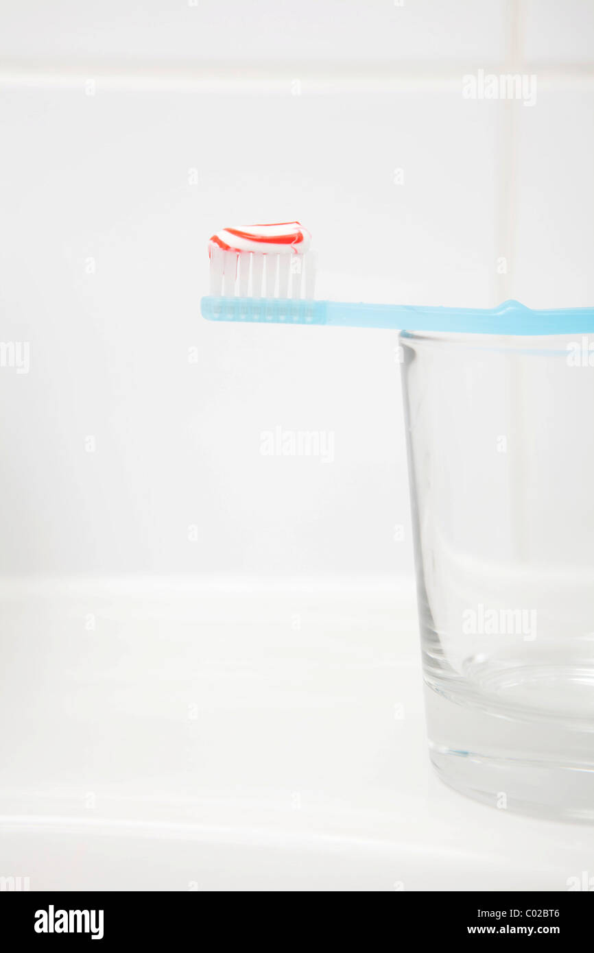 Zahnbürste mit Zahnpasta, Glas Stockfoto