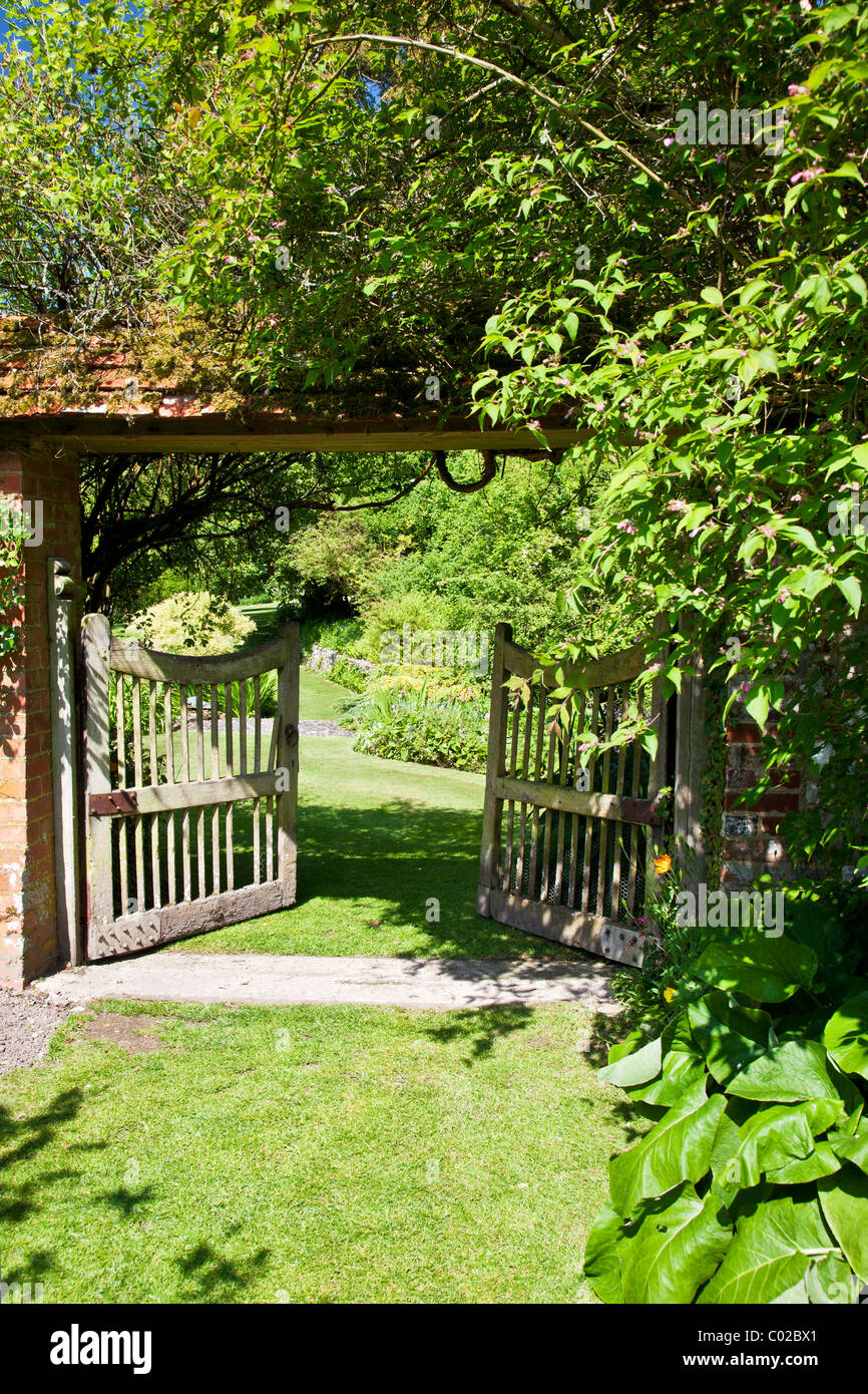 Eine offene Holz Gartentor in einem englischen Landhaus-Garten zeigt einen Blick auf die größeren Garten hinaus. Stockfoto