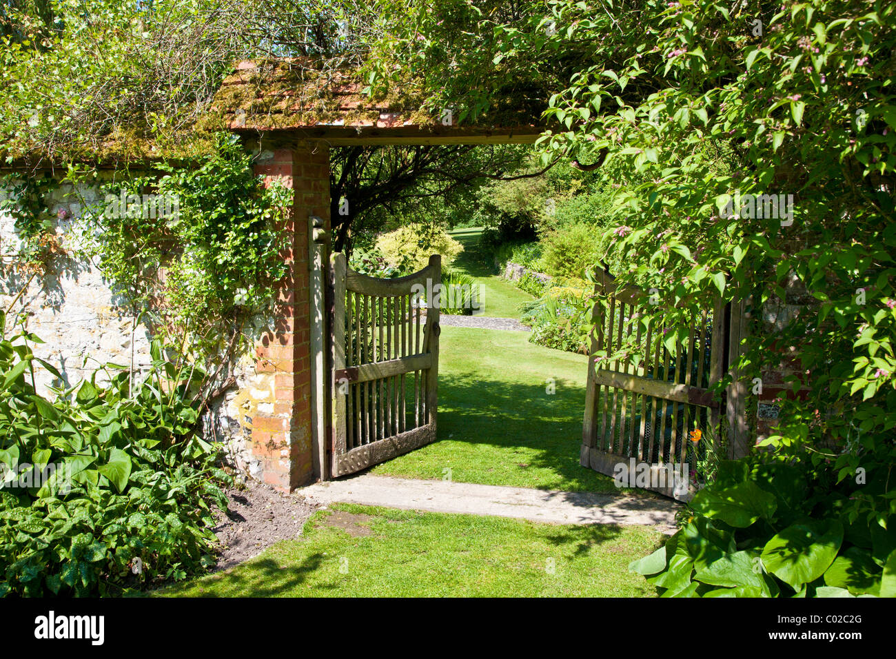Eine offene Holz Gartentor in einem englischen Landhaus-Garten zeigt einen Blick auf die größeren Garten hinaus. Stockfoto