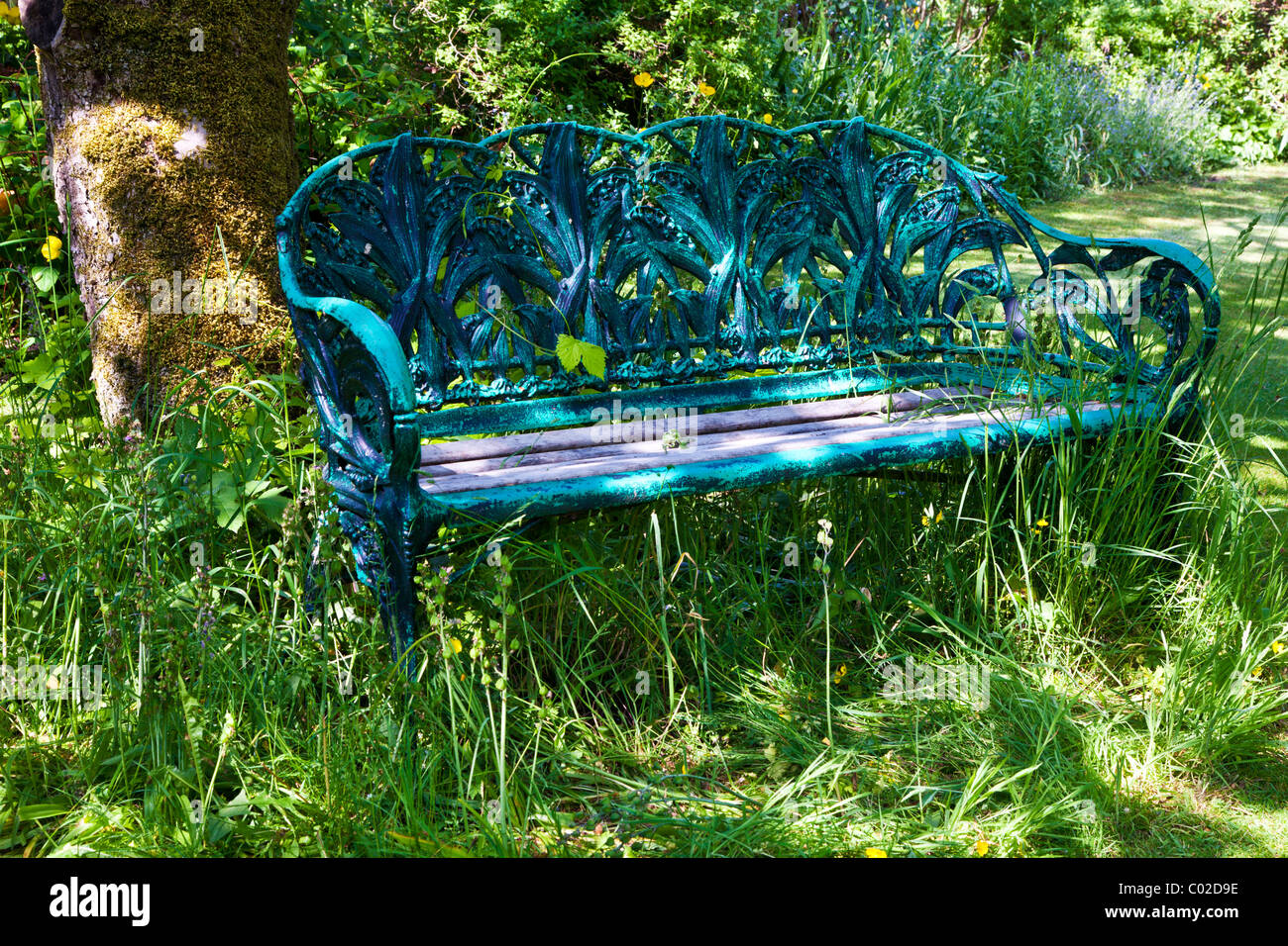 Ein ziemlich rustikal Schmiedeeisen Sitzbank oder Sitz in einer schattigen Ecke eines englischen Gartens im Sommer Stockfoto