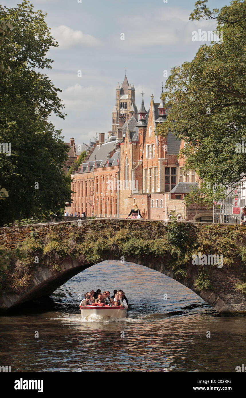 Ein Touristenboot unterquert eine kleine Straßenbrücke in zentralen Brügge (Brugge), Belgien. Stockfoto