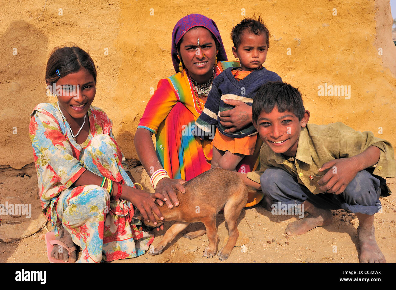 Eine indische Frau mit drei Kindern auf dem Boden saßen und hält einen kleinen Hund, Thar-Wüste, Rajasthan, Indien, Asien Stockfoto