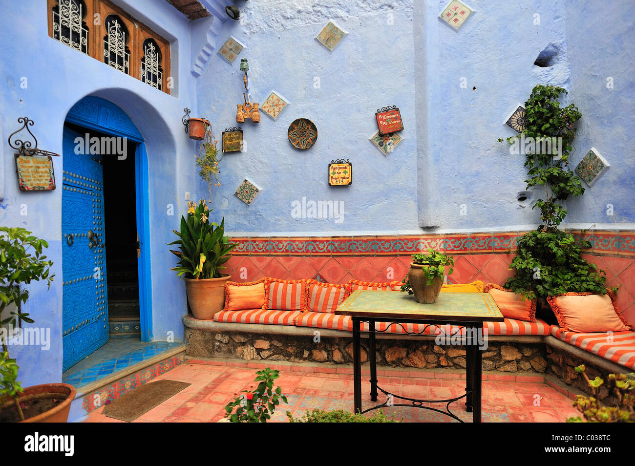 Haustür eines Hauses mit einem Sitzbereich und Pflanzen, Chefchaouen, Riff Bergen, Marokko, Afrika Stockfoto