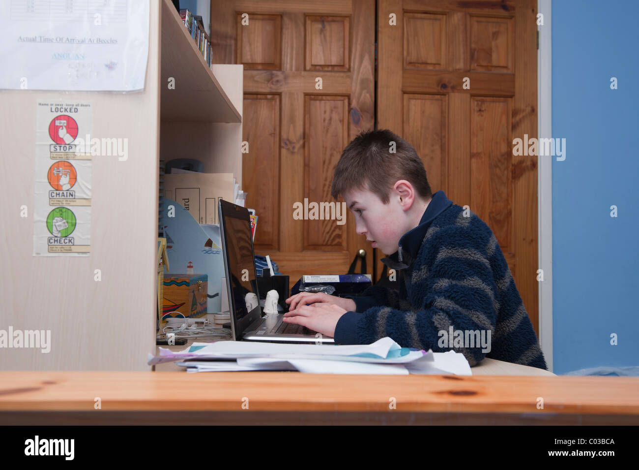 Ein MODEL Release Bild eines elfjährigen Jungen Hausaufgaben auf seinem Laptopcomputer in seinem Schlafzimmer Stockfoto
