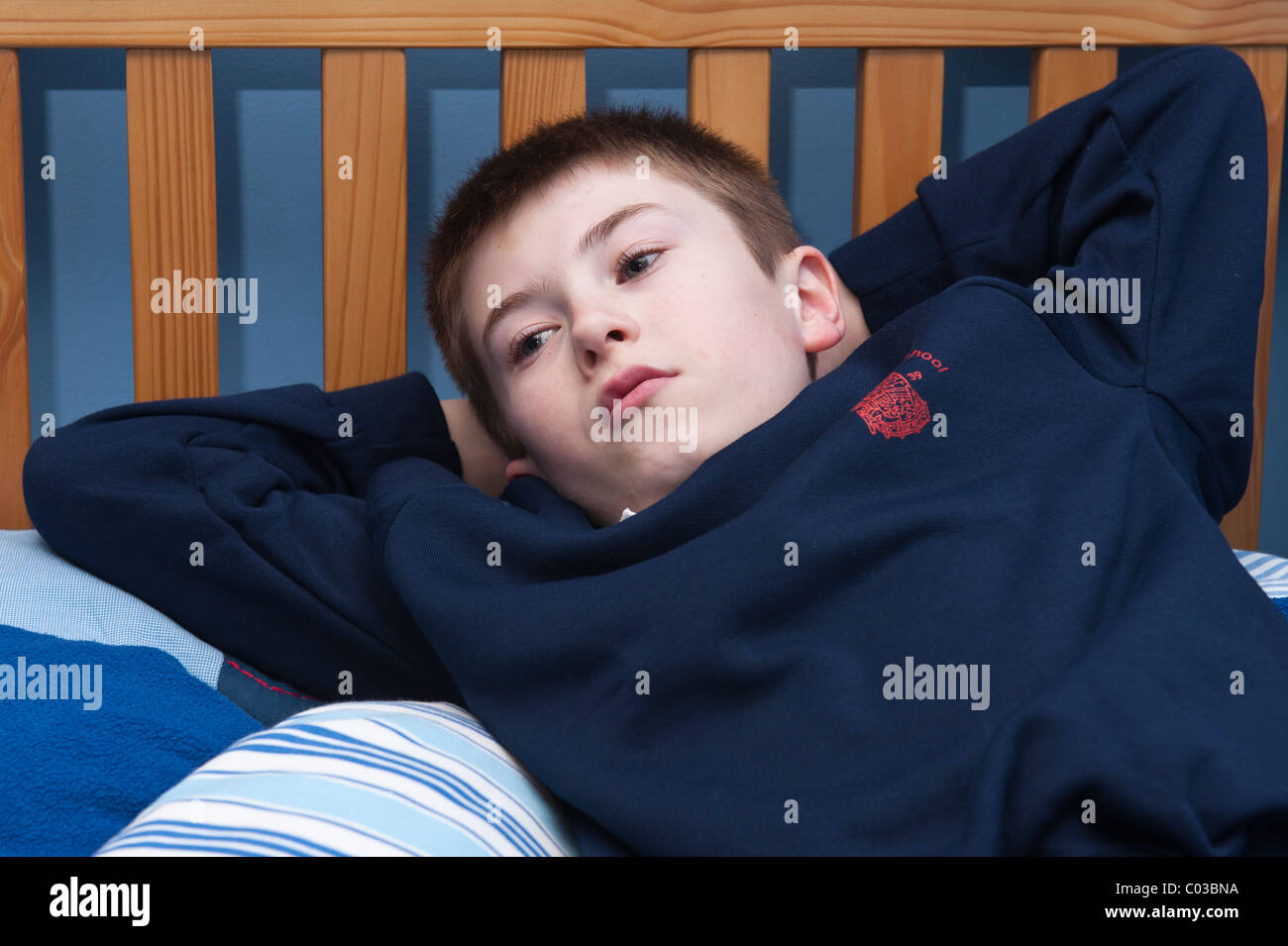 Ein MODEL Release Bild eines elf Jahre alten Jungen vor dem Fernseher in seinem Schlafzimmer im Vereinigten Königreich Stockfoto