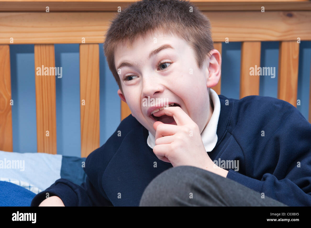 Ein MODEL Release Bild eines elfjährigen Jungen Kommissionierung seinen wackeligen Zahn in seinem Schlafzimmer im Vereinigten Königreich Stockfoto