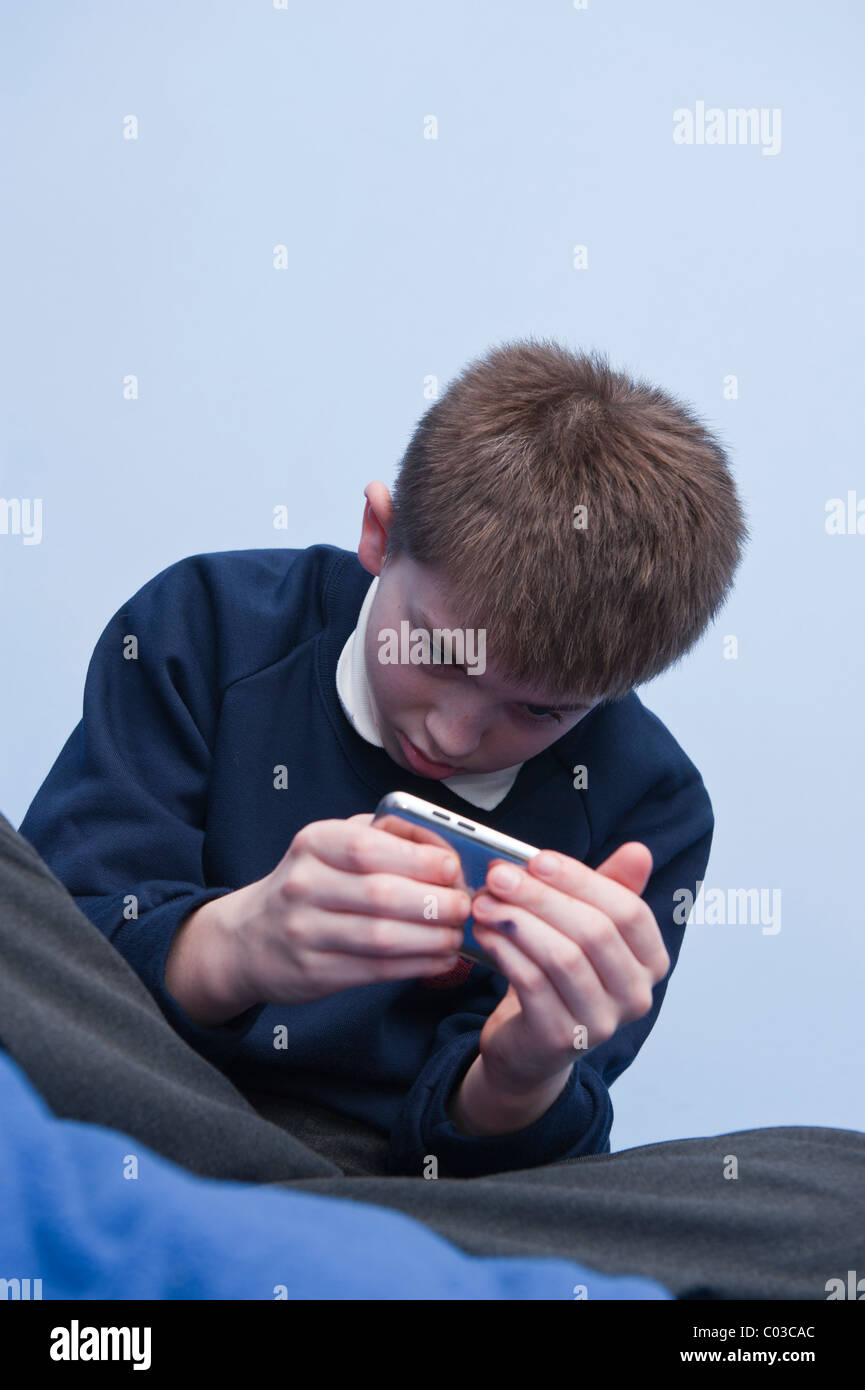 Ein MODEL Release Bild eines elfjährigen Jungen spielen mit seinem Ipod Touch in seinem Schlafzimmer im Vereinigten Königreich Stockfoto