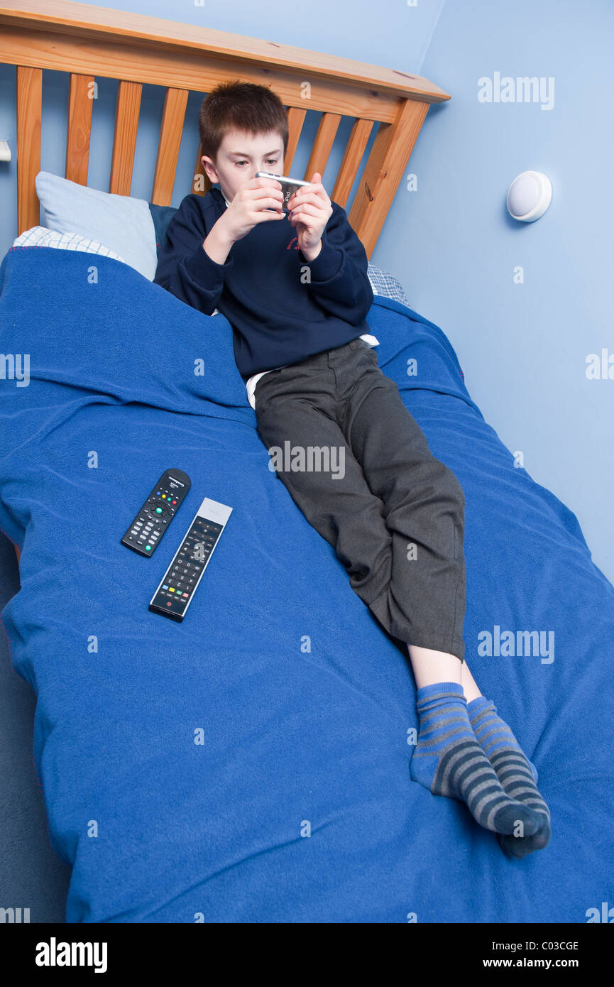 Ein MODEL Release Bild eines elfjährigen Jungen spielen mit seinem Ipod Touch in seinem Schlafzimmer im Vereinigten Königreich Stockfoto