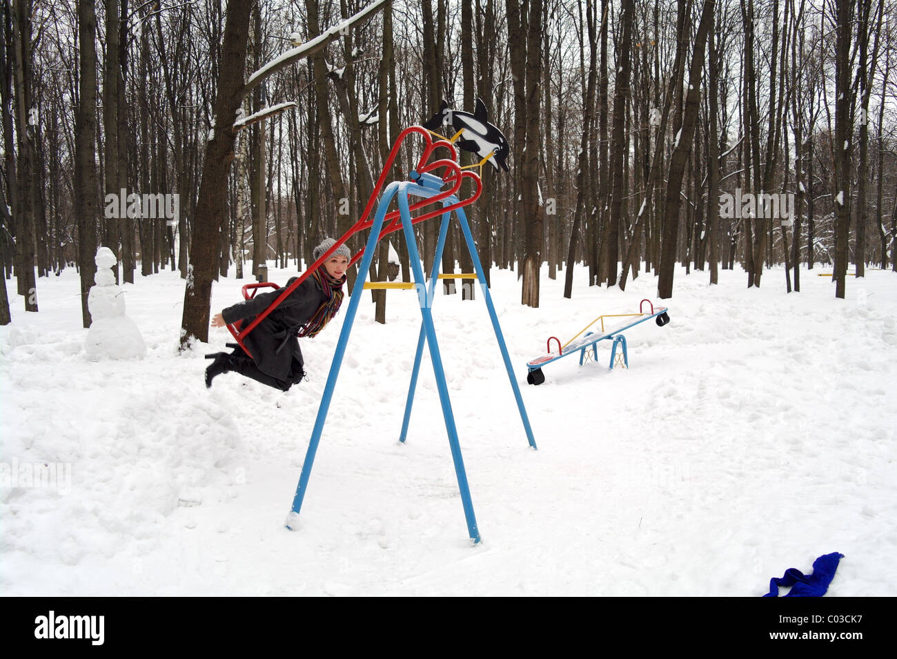 Das Mädchen geht für eine Fahrt auf eine Kinderschaukel mit Herz im Park im Winter, Moskau, Russland Stockfoto