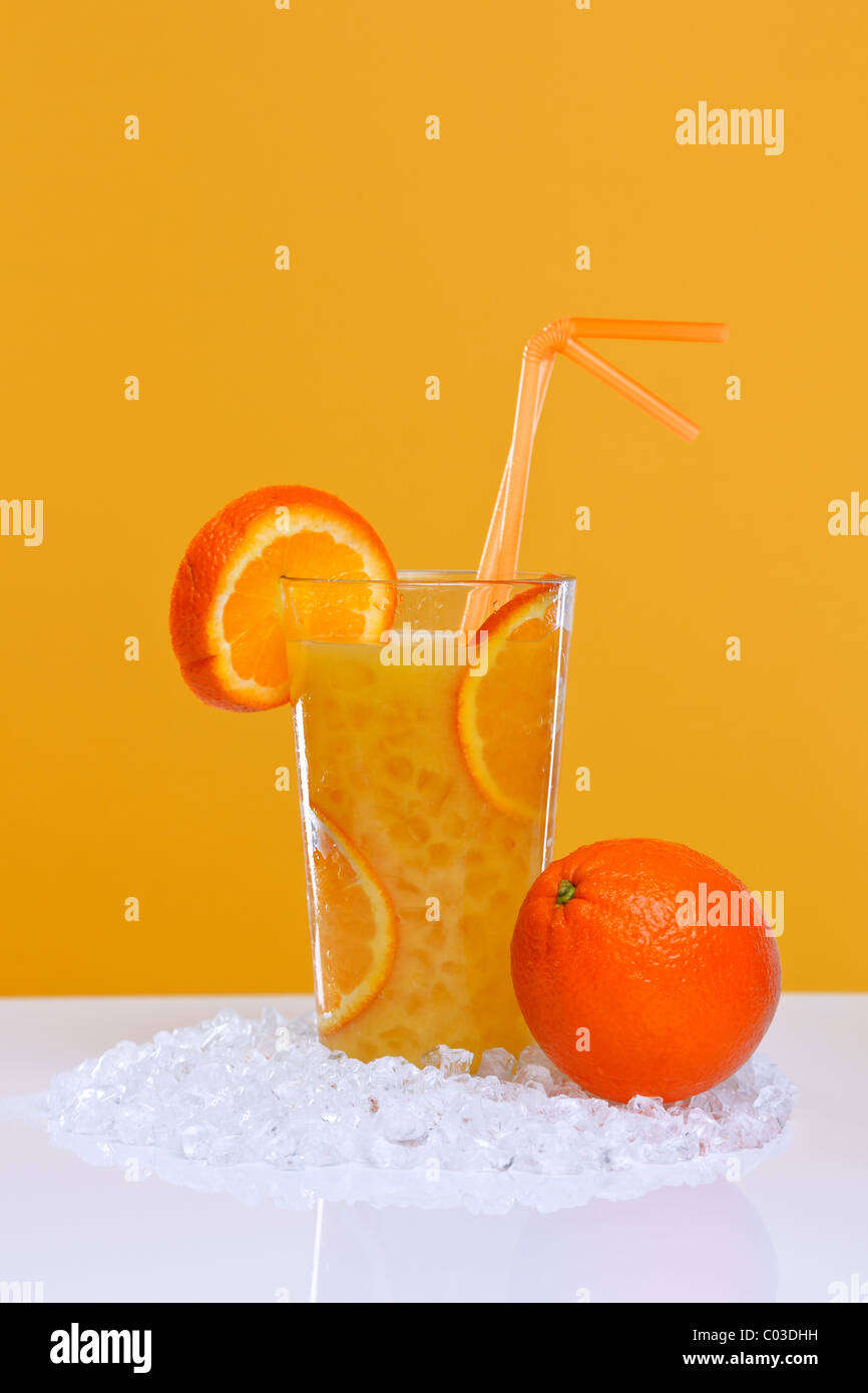 Foto von frisch gepressten Orangensaft in ein Glas mit crushed Ice auf orangefarbenem Hintergrund. Stockfoto