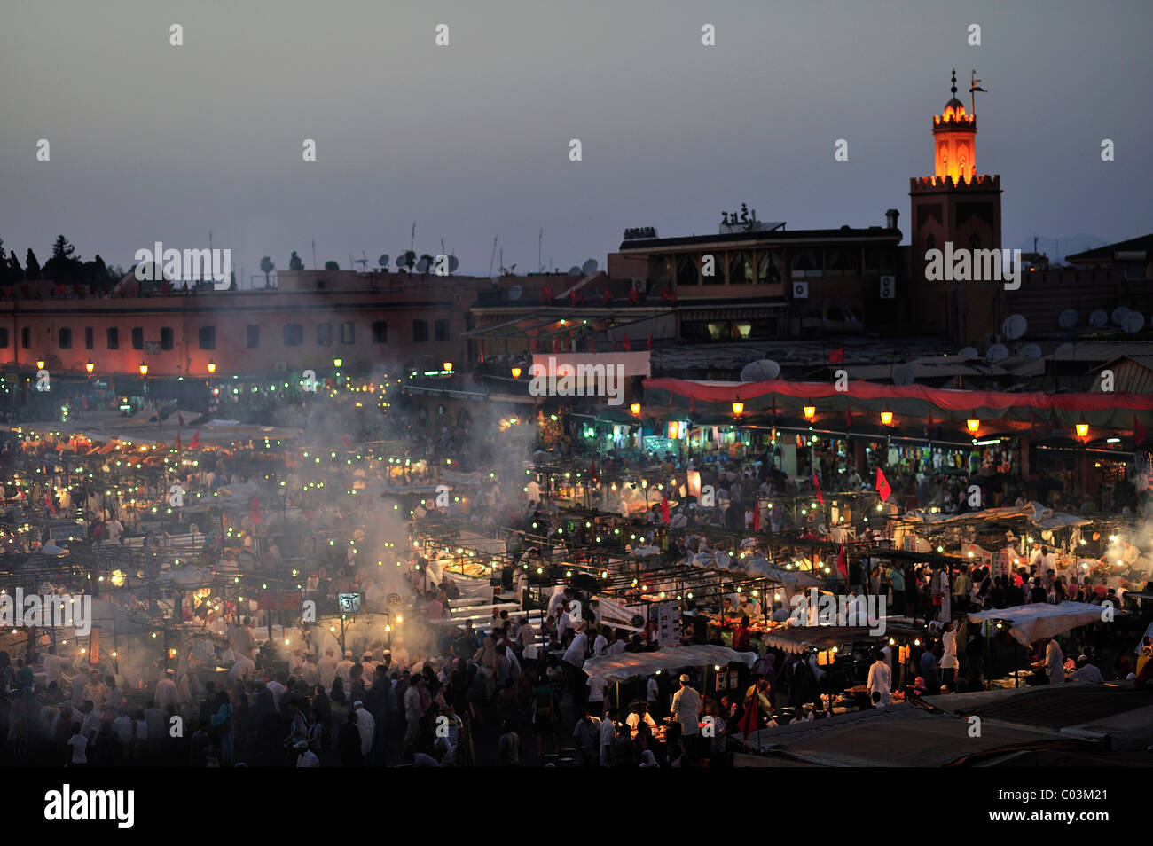 Abend auf dem Marktplatz Djemaa el Fna, wörtlich: Versammlung der Toten, mit Rauch aus den vielen Imbissbuden, hinter Stockfoto