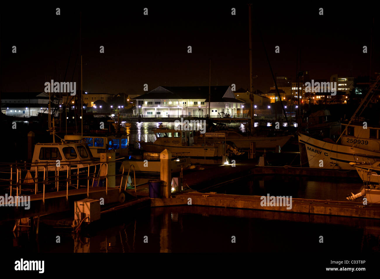 Nachtaufnahme der Fischerboote im Hafen und die Lichtreflexe. Lichter der Stadt im Hintergrund. Stockfoto