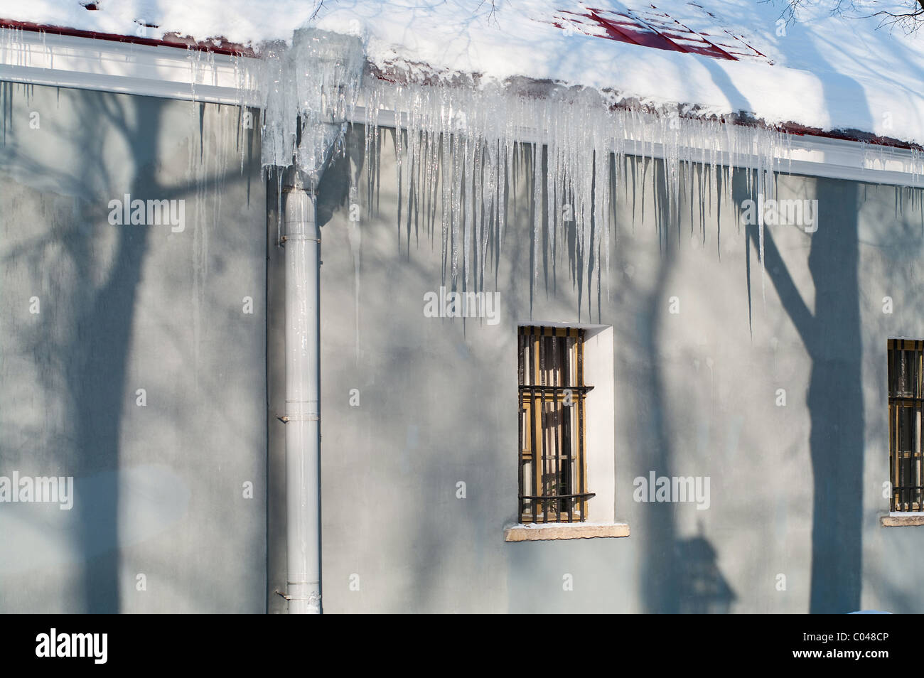 Eiszapfen hängen vom Dach des Hauses. Frühling in Russland. Jede Saison Probleme Stockfoto