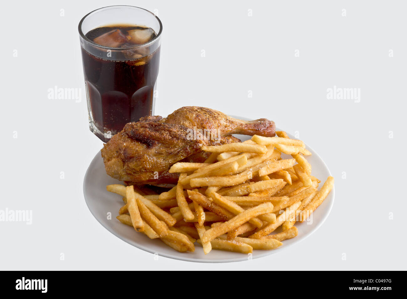 Platte gebraten Huhn mit Pommes frites neben eine kalte Cola. Isoliert Stockfoto