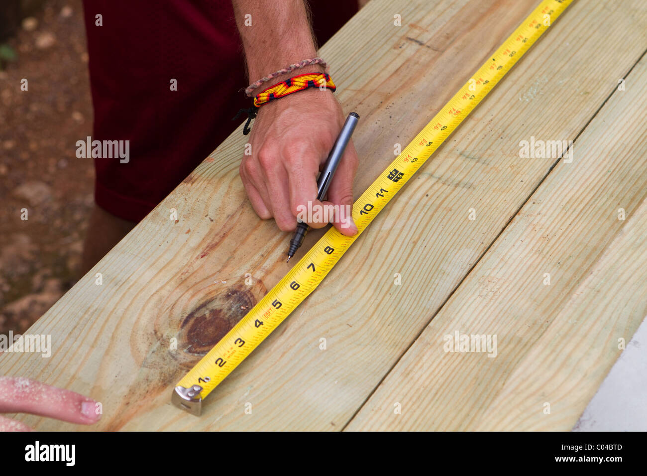 Der Mensch nutzt ein Maßband um die Länge der ein Stück Holz zu markieren. Stockfoto