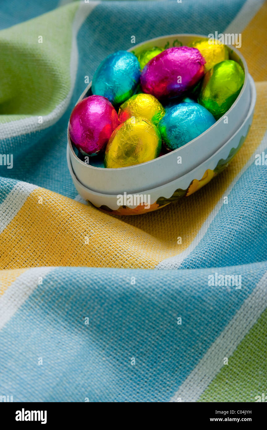 Mini Schokolade Ostereier im Karton Eierkarton auf strukturierte faltige gelbe und Blaue Tischdecke Stockfoto