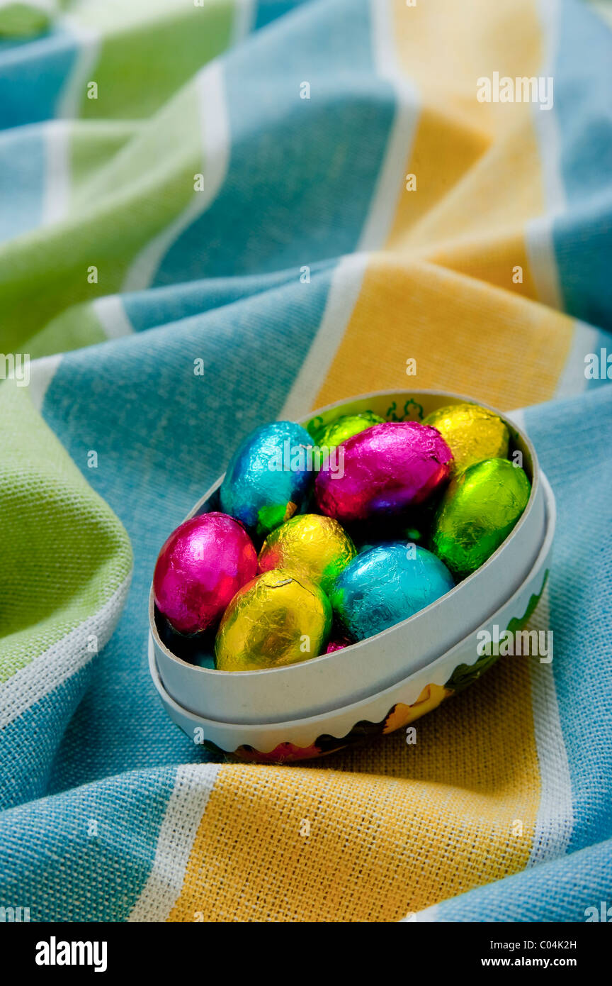 Mini Schokolade Ostereier im Karton Eierkarton auf strukturierte faltige gelbe und Blaue Tischdecke Stockfoto