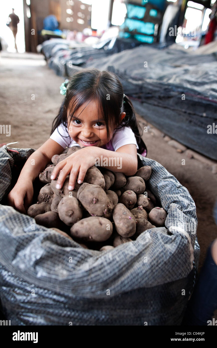 Ein junges Mädchen grinst hinter einer Plünderung Kartoffeln auf dem zentralen Markt in Ayacucho Peru Stockfoto